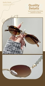 Detail of oval sunglasses featuring gold metal frame and black heart accents on lenses
