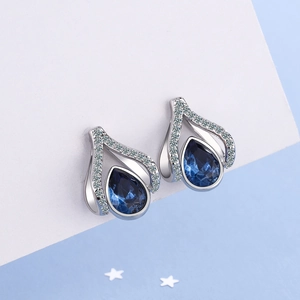 Silver teardrop earrings with dark blue crystal and white zircon stones on blue background