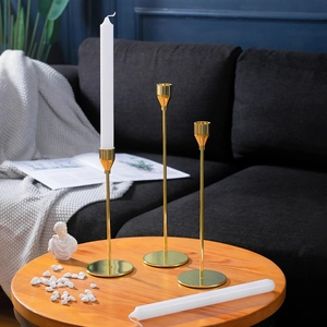Three gold metal candle holders of varying heights for elegant home table decoration