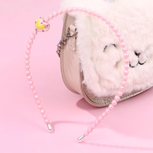Macro detail of a pink beaded headband for girls with a decorative heart charm