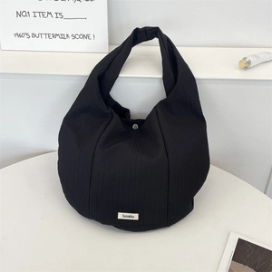 Détail d'un sac cabas en tissu plissé noir avec étiquette Sozakka et bouton pression