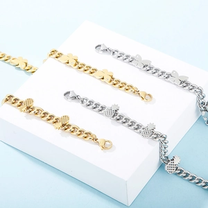 Detail of butterfly and pineapple pendants on gold and silver stainless steel bracelets