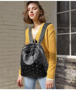Female model wearing a black vintage leather backpack with silver punk style metal rivets