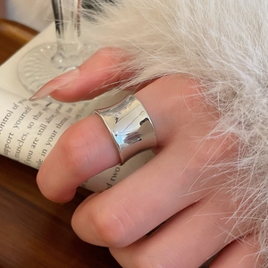 Polished silver wide open ring on model hand with feather and book background details