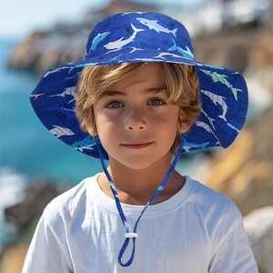 Close-up of kids sun hat with blue shark print and adjustable chin strap by the sea