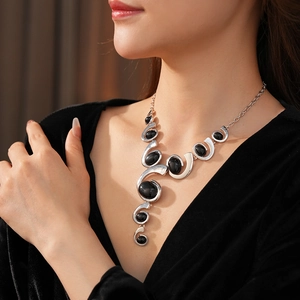 Close-up of geometric silver necklace with oval black gemstones on a model's neck