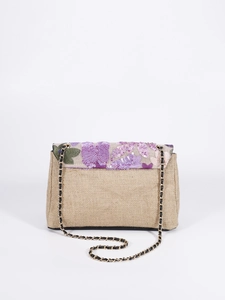 Detailed close-up of sequin floral embroidery on a beige woven jute shoulder bag