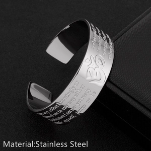 Detail view of silver stainless steel open bangle with engraved text on textured background