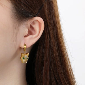 Detail of gold leopard head earrings with green stones and sparkling rhinestones