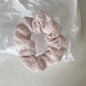 Nahaufnahme eines hellrosa Scrunchie mit plissiertem Chiffon auf weißem Hintergrund