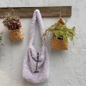 Detail of lavender plush shoulder bag with soft fleece texture and leather brand label
