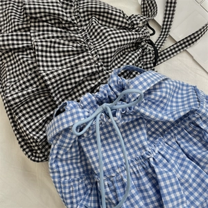 Detail of checkered drawstring tote bags in blue and black plaid with pleated fabric texture