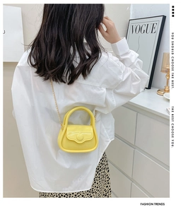 Chic yellow mini macaron jelly bag with golden chain worn on shoulder by a model