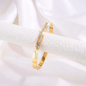 Detailed macro of gold-plated bangle featuring a row of square and round cubic zirconia
