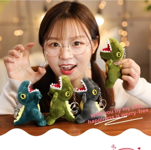 Detail of plush dinosaur keychains in various colors with metal rings on a soft backpack