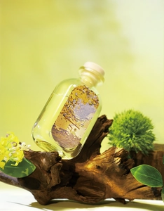 Detail of luxury reed diffuser bottle with impressionist art label on driftwood