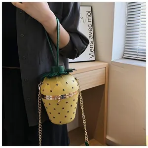 Détail d'un sac seau créatif fraise jaune avec chaîne en métal et décorations de feuilles