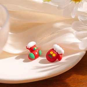 Detail of festive Christmas stocking and glove stud earrings on a white porcelain plate
