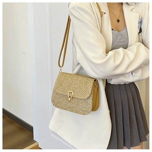 Close-up of woven yellow crossbody bag with gold horseshoe buckle and leather strap