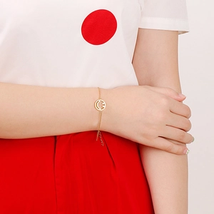 Close-up of a gold smile pendant bracelet on a wrist with minimalist design details