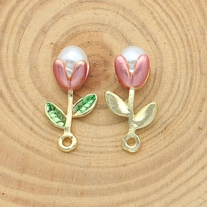 Detail of pink tulip flower charms with white pearl center on a rustic wood background