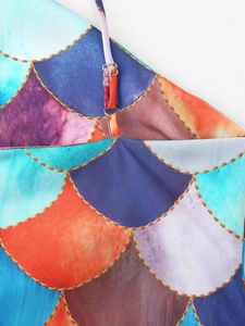 Close-up of mermaid scale print dress with golden chain pattern and metal strap buckle