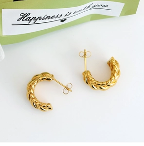 Detailed macro view of gold twisted rope U-shaped earrings with elegant C-curve design