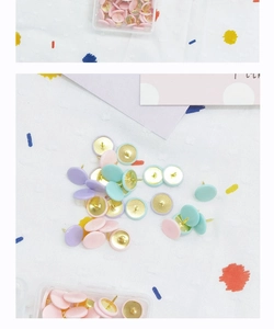 Gros plan de punaises pastel roses et menthe sur un fond en tissu texturé blanc