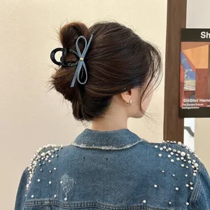Vue détaillée d'une pince à cheveux nœud en denim avec boucle dorée sur un chignon