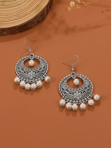 Detail of bohemian silver hollow earrings with floral engraving and white faux pearls