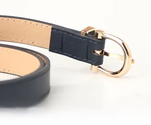 Detail of navy blue slim PU leather belt with elegant gold D-shaped metal buckle