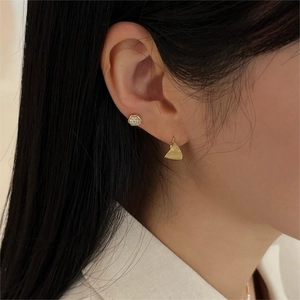 Detailed view of gold plated twisted hoop earrings and hexagonal studs on model