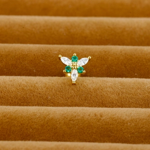 Macro view of gold flower cartilage earring with green and white marquise zircon stones