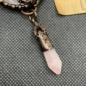 Detail of rose quartz pendant with antique bronze metallic carving and vintage texture