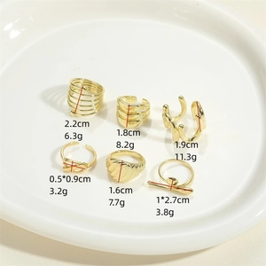 Minimalist gold croissant rings and earrings set shown on a white ceramic plate