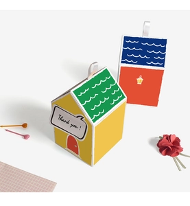 Detail of house-shaped colorful cookie gift boxes with white ribbon handles and text