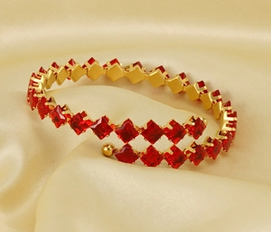 Macro shot of 18k gold plated spiral bangle with double row red zircon gemstone inlay