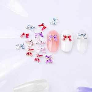 Bijoux d'ongles en forme de nœud avec émail coloré et strass présentés sur ongles
