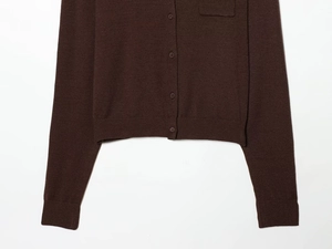 Detail of dark brown knit cardigan showing ribbed cuffs and neat button closure