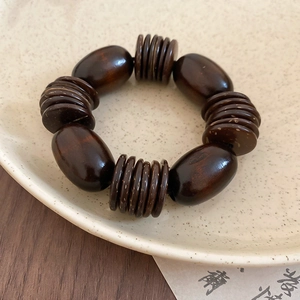 Detail of vintage coconut shell and wood bead bracelet on a ceramic tray