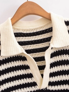 Dettaglio polo in maglia a righe bianche e nere con colletto bianco e scollatura a V