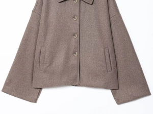 Detailed view of brown woolen short jacket featuring lapel collar and button pockets