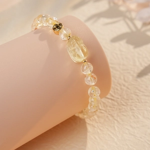 Detail of beaded quartz bracelet with golden coin charm on elegant display