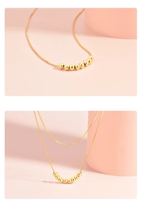 Macro detail of a 925 silver plated golden layered beaded necklace on pink background