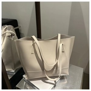 Dettaglio di una borsa tote grande minimalista in pelle bianco crema su libri decorativi