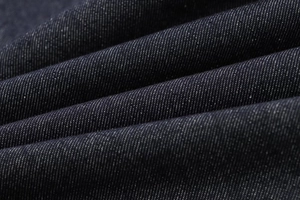 Detailed macro view of dark denim fabric showing diagonal twill texture and weave