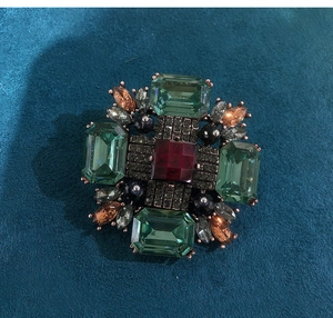 Detailed view of vintage cross brooch featuring emerald-cut crystals and red center stone