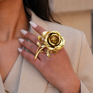 Close-up of a large vintage gold rose ring with intricate layered petals on a model hand