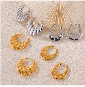 Detailed view of U-shaped gold and silver earrings on a white coral decorative stand