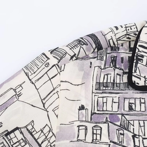 Close-up of cream shirt featuring purple city print and black contrast piping detail